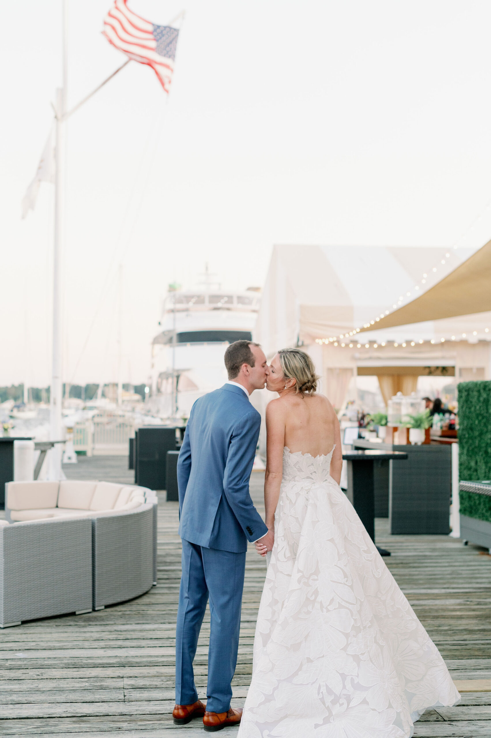 Bride and groom kiss on a dock on Newport Harbor.